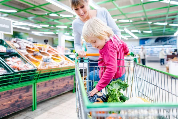 Anya, amelynek a kisgyermek lovaglás bevásárlókosár szupermarket — Stock Fotó