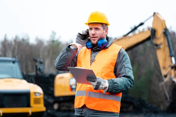 Porträtt av en stenbrott arbetstagare står framför grävmaskin — Stockfoto