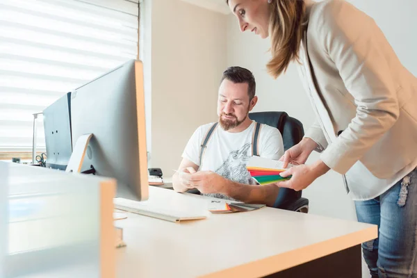 Creativos trabajando en equipo revisando colores para proyecto publicitario — Foto de Stock