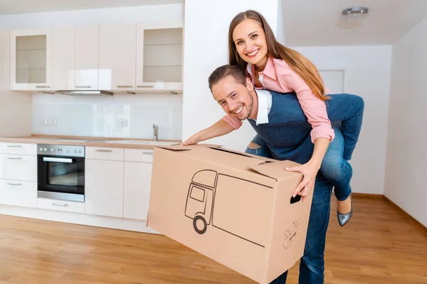 Man carrying his wife and a moving box into the new apartment — Stock Photo, Image