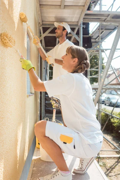 Pintora mujer pintando una pared con pintura amarilla — Foto de Stock