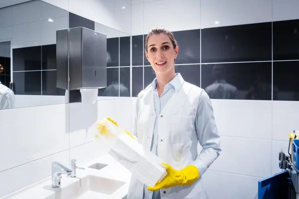 Janitor mulher trocando toalhas de papel no banheiro público — Fotografia de Stock