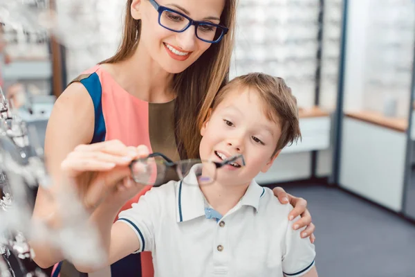 Madre e hijo disfrutan tanto de las gafas que se ofrecen en la tienda de óptica —  Fotos de Stock