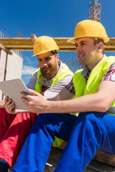 Arbeiter lesen oder sehen während der Arbeitspause ein Video auf einem Tablet-PC — Stockfoto