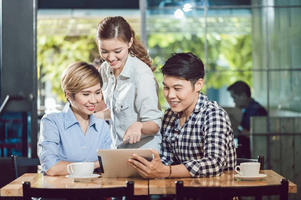 Amigos olhando para tablet digital sentado no café — Fotografia de Stock