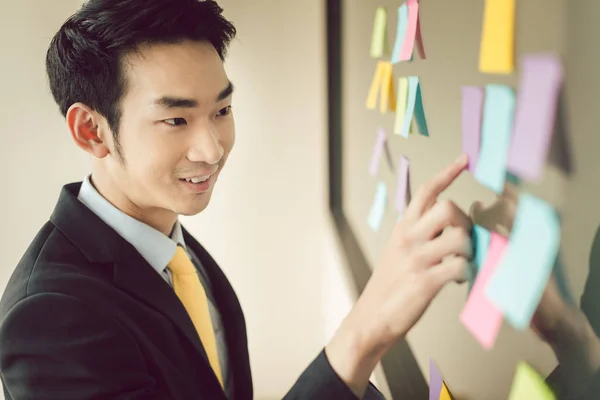 Young businessman pointing at sticky note — Stock Photo, Image