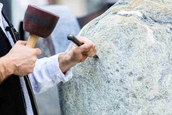 Sculptor with mallet and cutter working on erratic block — Stock Photo, Image