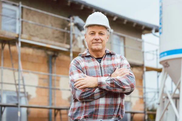 Orgulhoso estucador de pé em frente ao andaime no canteiro de obras — Fotografia de Stock