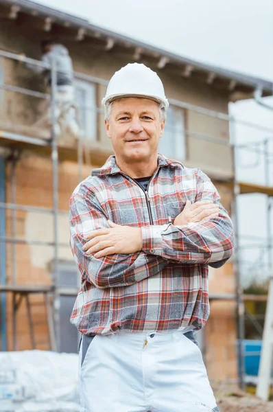 Orgulloso yesero de pie frente al andamio en el sitio de construcción —  Fotos de Stock