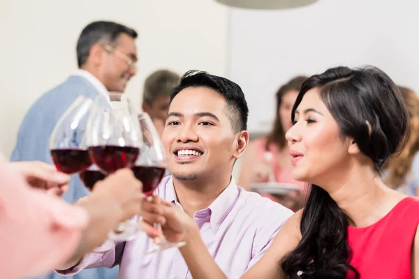 Couple toasting wineglasses with friends — Stock Photo, Image