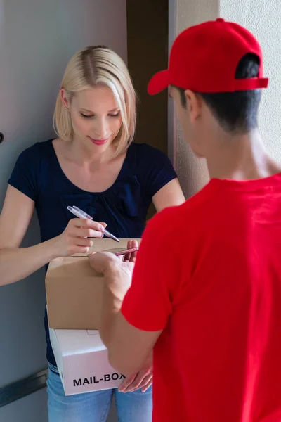 Frau unterschreibt auf Gerät für Paketzustellung — Stockfoto