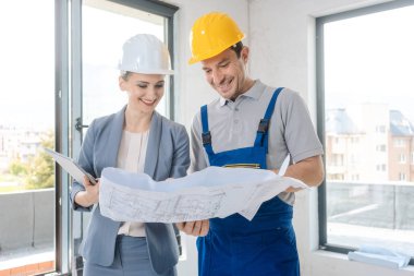 İnşaat işçisi ve planı sitede bakarak mimar
