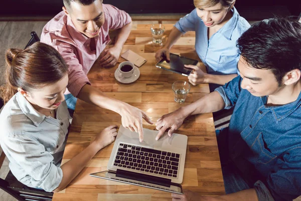 Gruppe von Freunden schaut im Restaurant auf Laptop — Stockfoto