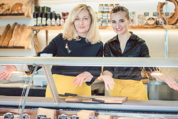Twee salesladies bij de balie van de kaas het aanbieden van hun goederen — Stockfoto
