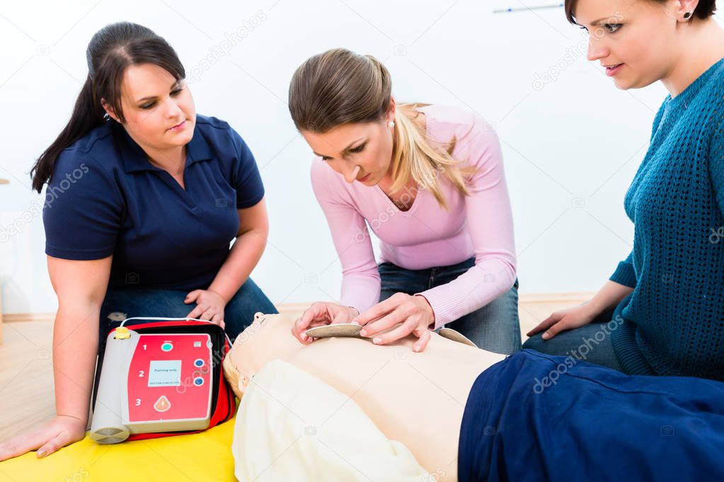 Attendees of first aid class learning how to use defibrillator 