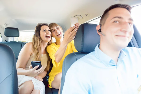 Kvinnor i taxi tar selfies med sina telefoner — Stockfoto