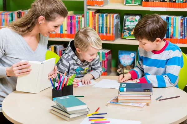 Mor läsebok från biblioteket till sin son — Stockfoto