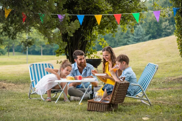 Rodiče dvou dětí poslechu jejich syn mluví během rodinný piknik — Stock fotografie