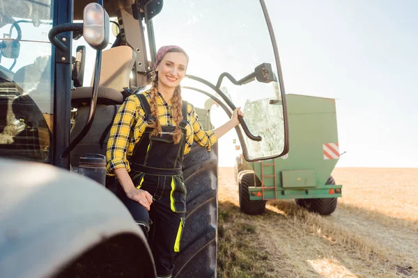 Mulher agricultor em pé na frente do trator no campo de trigo — Fotografia de Stock