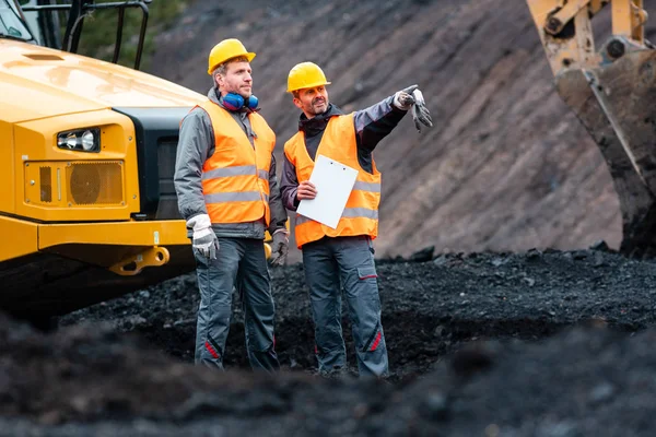 Worker with a plan and a clipboard discussing things in quarry — Stock Image Worker with a plan and a clipboard discussing things in quarry Royalty Free Stock Images