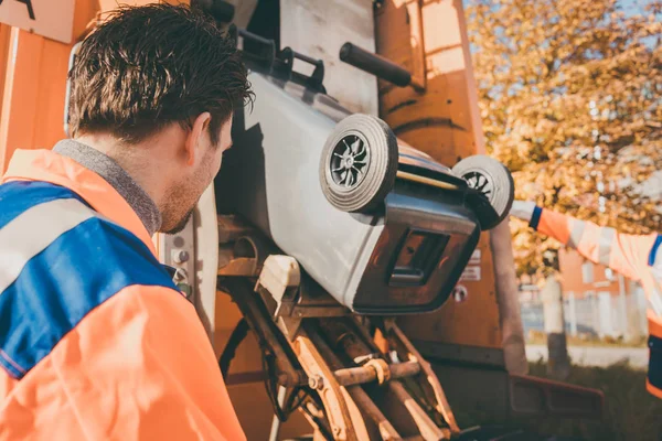 Trabajador vaciando cubo de basura en vehículo de desecho — Foto de Stock