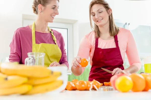 Frau schaut ihren Freund beim Orangenschneiden an — Stockfoto