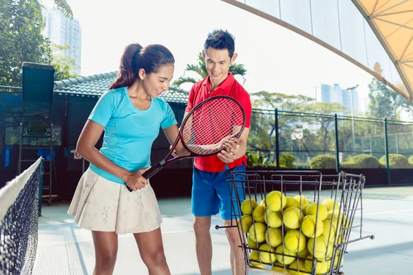 Instrutor de tênis ensinando o aperto correto para segurar a raquete — Fotografia de Stock