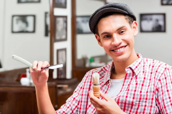 Smiling hairdresser holding razor and shaving brush — Stock Photo, Image