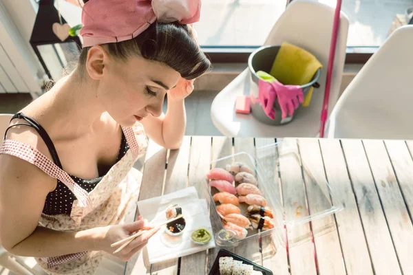 Dona de casa mulher descansando de tarefas domésticas comer algum sushi — Fotografia de Stock