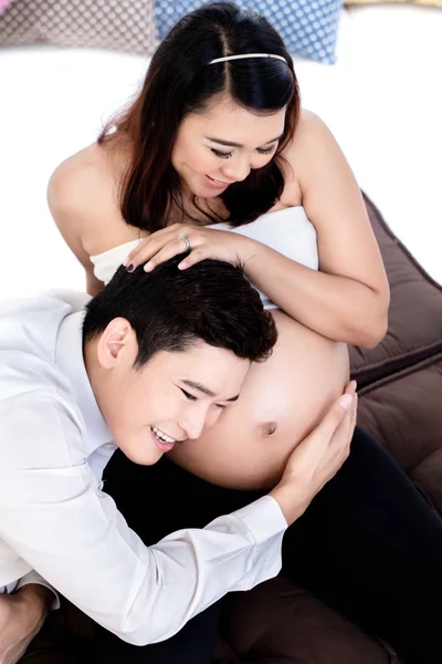 Glimlachende man luisteren naar zijn zwangere vrouw buik — Stockfoto