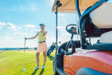 Golf sahasında cep telefonunda konuşan neşeli kadın
