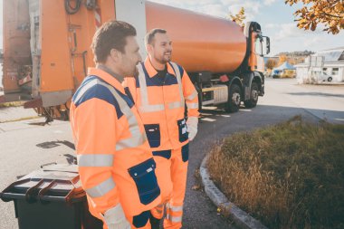 Two garbage removal service workers having short break clipart