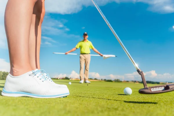 Bola de golfe no putting green atrás da seção baixa de um jogador do sexo feminino — Fotografia de Stock