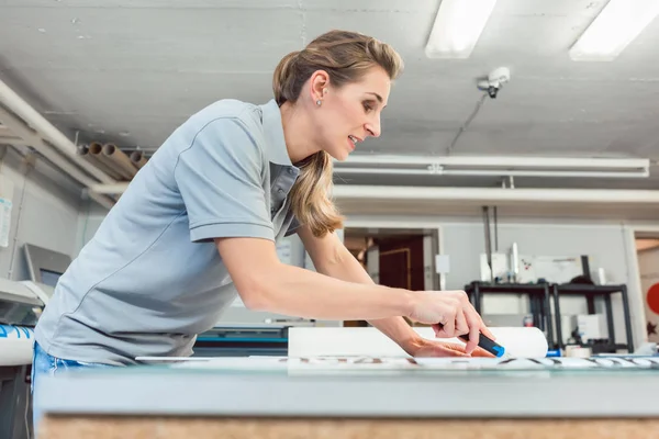 Frau schneidet Schilder oder Vinylfolien zur Herstellung von Werbematerial — Stockfoto