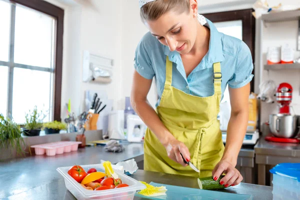 Female chef cutting cucumber with knife — Stock Photo, Image