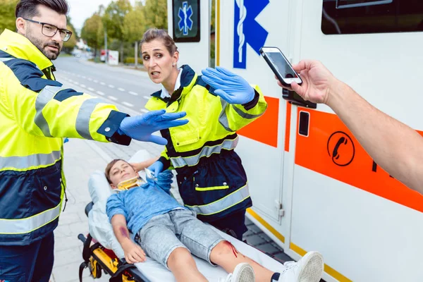 Paramedics fighting people trying to make photos of accident — Stock Photo, Image