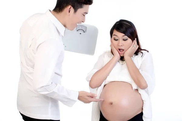 Muž, který drží váhu, ukazuje prstem na jeho těhotný břicho — Stock fotografie