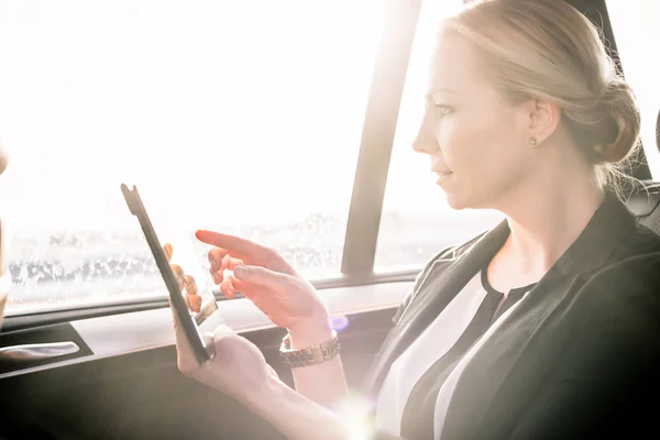 Businesswoman touching digital tablet screen in car — Stock Photo, Image