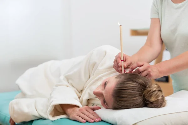 Terapeut hand med brinnande öra ljus i kvinnas öra — Stockfoto