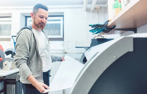 Man working on large format printer in advertising material agency — Stock Photo, Image