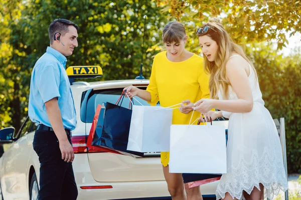 Dvě ženy přicházející z nákupního výletu pomocí taxíku — Stock fotografie