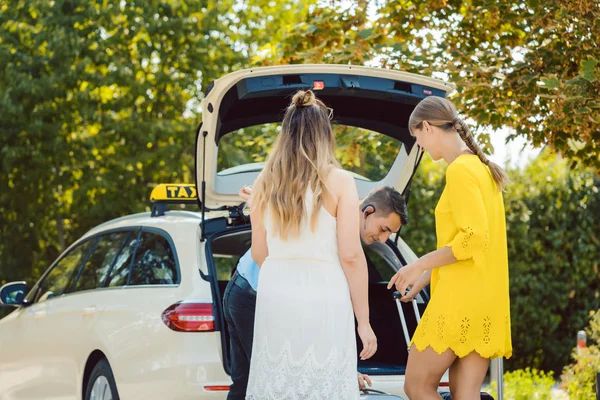 Οδηγός ταξί βάζοντας αποσκευές των γυναικών στο πορτ-μπαγκάζ του αυτοκινήτου — Φωτογραφία Αρχείου