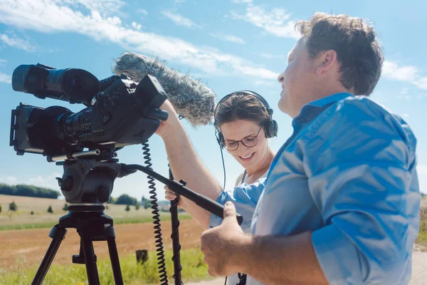 Cameraman with his camera and assistant working in production — Stock Photo, Image