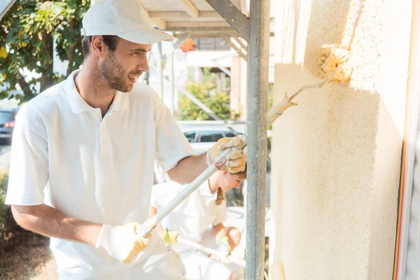 Maler auf Baustelle streicht Wand gelb — Stockfoto