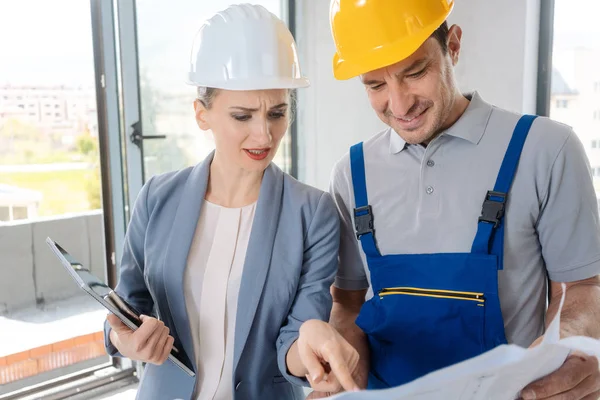 Trabajador de la construcción y arquitecto mirando el plan en el sitio — Foto de Stock