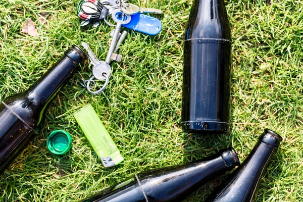 Garrafas de álcool, isqueiro e chaves na grama — Fotografia de Stock