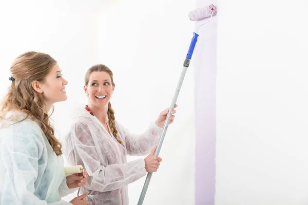 Mujer mirando a su amigo pintando la pared — Foto de Stock