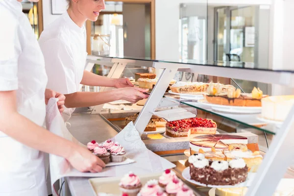 Les femmes en pâtisserie remplissent l'affichage des ventes avec des tartes — Photo