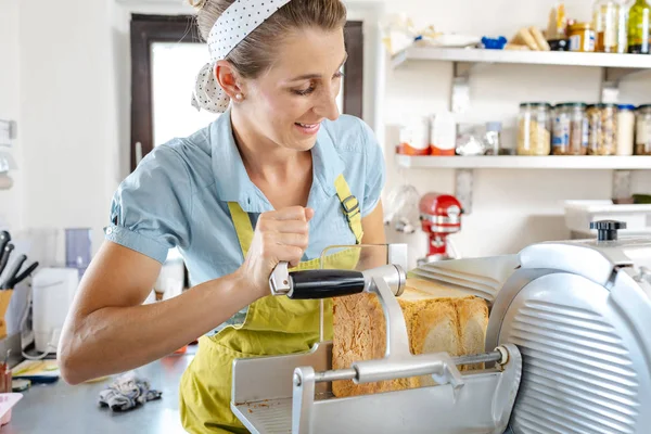 Gelukkige vrouw die brood in de machine zet — Stockfoto