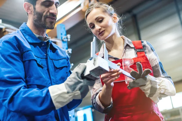 Operaio donna e uomo che verifica le misure del pezzo in metallo — Foto Stock